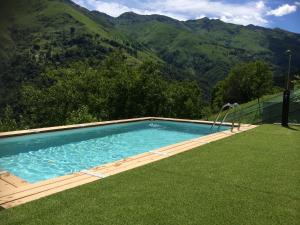 a swimming pool in the grass with mountains in the background at Chalet con Piscina in Garzeno +43 photos