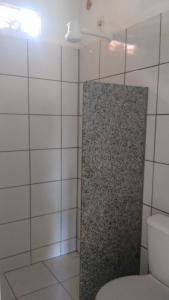 a bathroom with a toilet and a tiled wall at Chalés do Otto e Karine in Canoa Quebrada