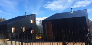 two black buildings with mountains in the background at La melliza in San Carlos de Bariloche