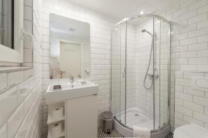 a white bathroom with a sink and a shower at Tatra 4 Studios in Budapest
