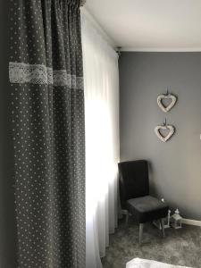 um quarto com uma cortina, uma cadeira e uma janela em U Macieja em Klodzko