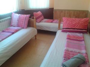 two beds in a room with pink and white pillows at Osogovo Rooms in Sofia