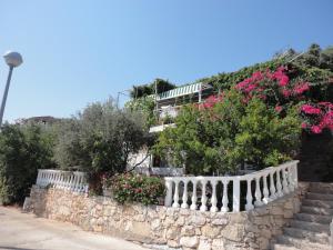 a white fence with flowers on a stone wall at Apartment Ljilja in Blato