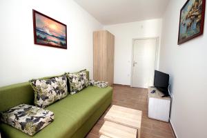 a living room with a green couch and a television at Apartments Centar Sutomore in Sutomore