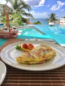 a white plate with an omelet and fruit on a table at La Vista Resort in Simpson Bay