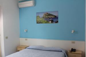 a bedroom with a bed with a blue wall at Aparthotel Villa Marinù in Ischia