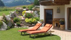 貝旺的住宿－豪斯穆薩蘭公寓，花园里的草地上摆放着两把橙色椅子