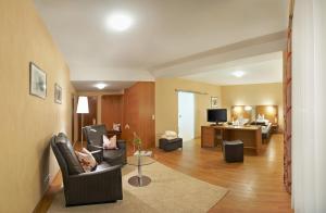 a living room with chairs and a couch and a television at Flair Hotel Adlerbad in Bad Peterstal