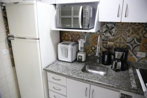 una pequeña cocina con fregadero y nevera. en Apartamento central, novo e com garagem em Curitiba, en Curitiba