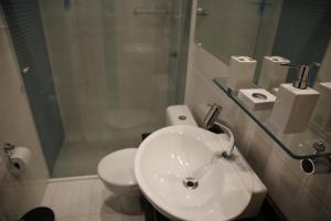 a bathroom with a sink and a toilet and a shower at Apartamento central, novo e com garagem em Curitiba in Curitiba
