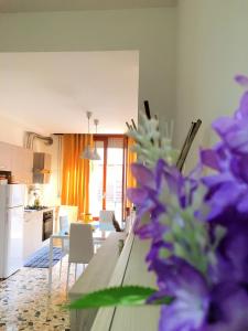 cocina y sala de estar con mesa con flores púrpuras en Vittoria Colonna, en Vittoria