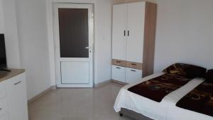 ein weißes Schlafzimmer mit einem Bett und einem Fernseher in der Unterkunft Apartament Bogoridi in Burgas City