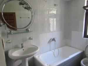 a bathroom with a sink and a tub and a mirror at Apartamente plazhi in Sarandë +39 photos