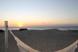 una hamaca en la playa con la puesta de sol en el fondo en Arenas del Mar, en Punta del Diablo