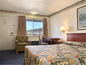 a hotel room with a bed and a chair at Days Inn by Wyndham Yuba City in Yuba City