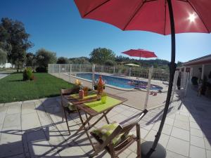a patio with a table and an umbrella next to a pool at Farmer Fraguas in Rio Maior