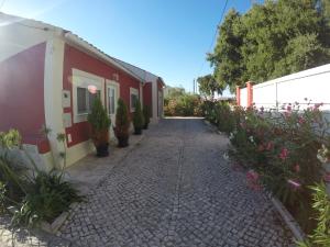 a walkway next to a red building with flowers at Farmer Fraguas in Rio Maior