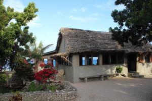 a house with a thatched roof with flowers in front at Rocky Ridge Bungalows in Tanna Island
