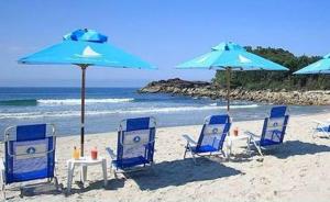 a group of chairs and tables and umbrellas on a beach at Pousada Armação de Camburi in Camburi