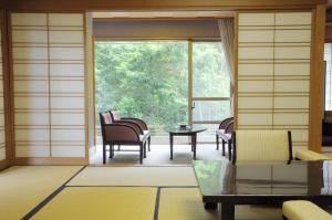 Habitación con sillas, mesa y ventana en Yugawara Onsen Kawasegien Isuzu Hotel, en Atami