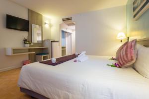 a bedroom with a large white bed with flowers on it at ON Hotel Phuket - SHA in Karon Beach