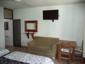 een woonkamer met een bank en een tv aan de muur bij Hotel Ocampo in Oaxtepec