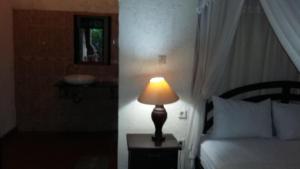 una lámpara sentada en una mesa junto a una cama en Three Brothers Bobby's Villas, en Amed