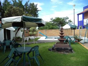 a table and chairs with an umbrella and a fountain at Hotel Ocampo in Oaxtepec