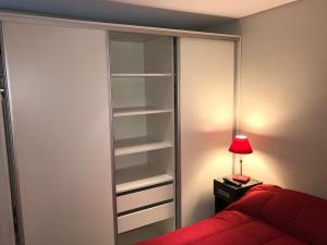 1 dormitorio con armario, cama roja y lámpara en Marco Polo Natura Apartamento en Mar del Plata
