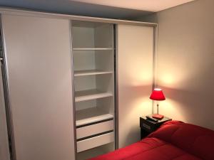 a bedroom with a closet with a red bed and a lamp at Marco Polo Natura Apartamento in Mar del Plata