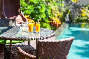 a table with two drinks on it next to a pool at Ungasan Beach Villas in Uluwatu