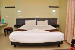 a bedroom with a large bed with white sheets at Hotel Rajam in Kanyakumari
