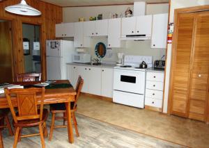 a kitchen with white appliances and a table and chairs at Oasis du grand fond Inc in La Malbaie