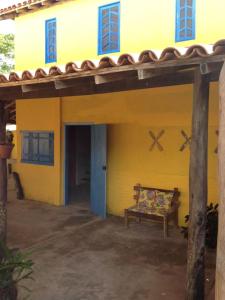 una casa gialla con una panchina davanti di Arte Vida Hostel a Itaúnas