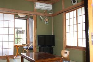 a living room with a tv and a table and windows at Umeya Annex in Fujikawaguchiko