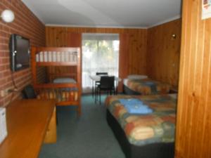 a room with two beds and a desk and a bunk bed at Orbost Country Road Motor Inn in Orbost