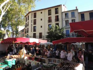 a group of people walking around a market with umbrellas at Hotel des Arcades in Céret