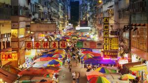 una concurrida calle de noche con sombrillas en Pop Inn Mong Kok, en Hong Kong