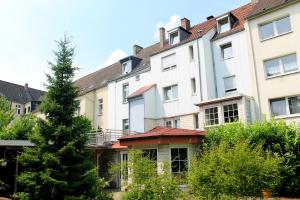 un edificio de apartamentos con un árbol delante en TM Apart Hotel Essen, en Essen