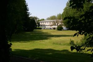 una casa grande en medio de un campo de hierba en Hostellerie de la Quenoeuille, en Marquise