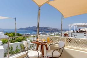 balkon ze stołami i krzesłami oraz widokiem na ocean w obiekcie Enalion White Suites Oia w mieście Oia