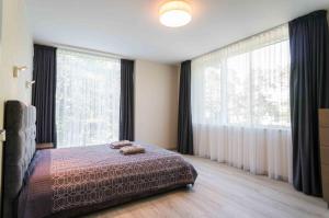 a bedroom with a bed and a large window at Apartamentai Voveraite in Palanga