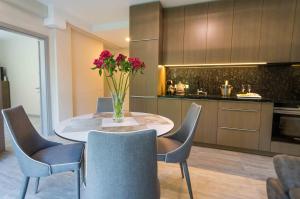 uma cozinha com uma mesa com cadeiras e um vaso de flores em Apartamentai Voveraite em Palanga