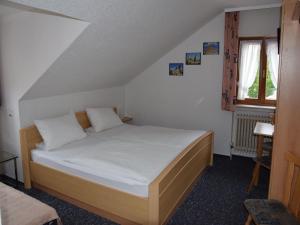a bedroom with a bed with white sheets and a window at Hotel Gästehaus Sonne in Sinsheim