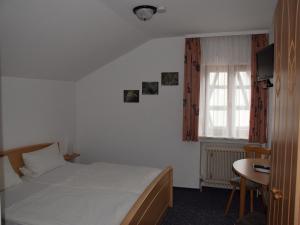 een slaapkamer met een bed, een tafel en een raam bij Hotel Gästehaus Sonne in Sinsheim