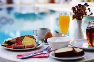 una mesa con platos de comida y un vaso de zumo de naranja en Santellini Hotel, en Kamari