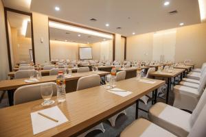 a conference room with tables and chairs and a screen at Whiz Prime Hotel Sudirman Makassar in Makassar