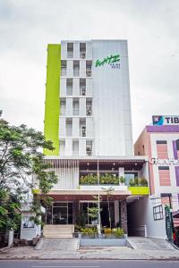 ein Hotelgebäude mit einem grünen Schild darauf in der Unterkunft Whiz Prime Hotel Sudirman Makassar in Makassar