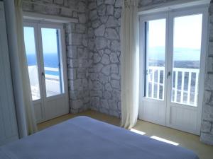 a bedroom with doors and windows with a view of the ocean at Milo Milo Suites in Mandrakia +37 photos