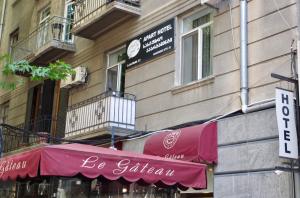 una tienda con un toldo rojo al lado de un edificio en Apart Hotel GH, en Tiflis